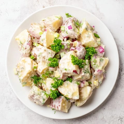 A big bowl of creamy Potato Salad, ready to be served cold at a summer picnic.