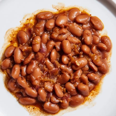Hearty Baked Beans, bubbling in a Dutch oven with a smoky aroma, perfect for a cozy supper.