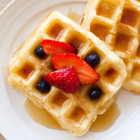 Fluffy and delicious waffles, piled high and steaming, ideal for a satisfying breakfast treat.