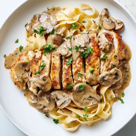 Garlic and herbs perfume this rich Chicken Marsala, presented in a white bowl with fresh parsley and Parmesan garnish.