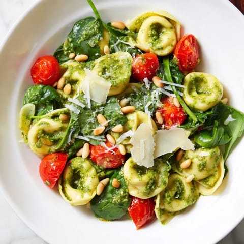 Pesto Tortellini Salad served chilled, featuring cheese tortellini, juicy tomato halves, and a glossy basil pesto dressing.