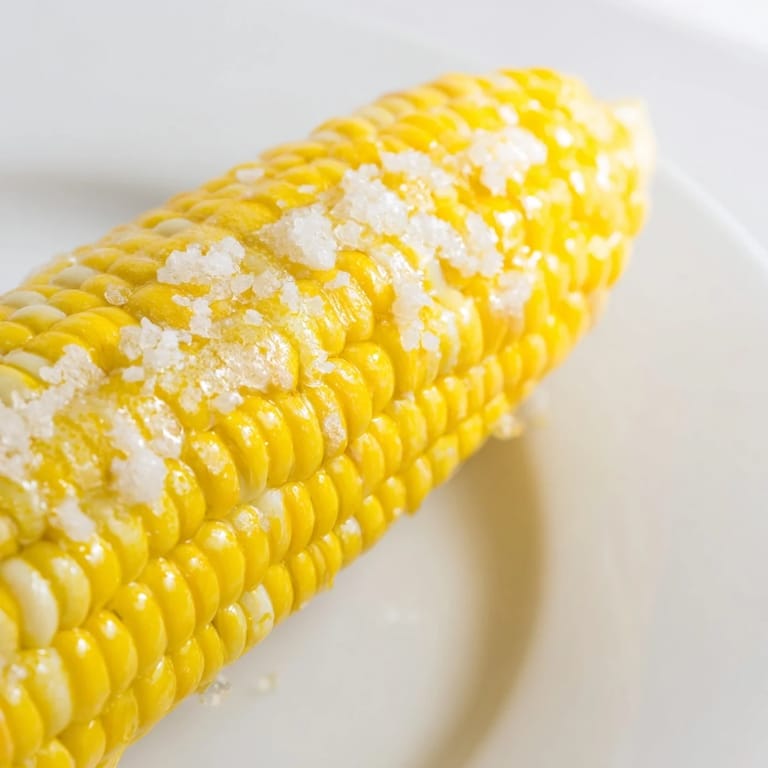 Grilled corn on the cob with charred kernels, a delicious summer side dish, buttered.