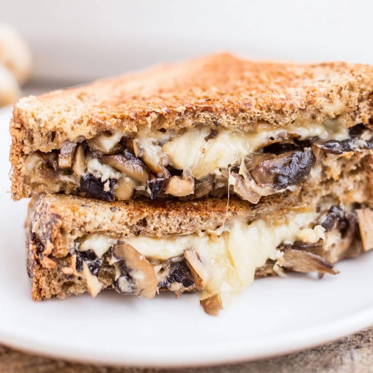 A close-up of the savory Mushroom Swiss Grilled Cheese, featuring bubbling cheese and golden-brown crusty bread.