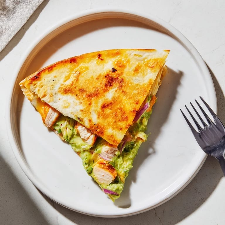 Fresh cilantro garnishes a platter of warm, homemade Chicken Avocado Quesadilla slices ready to serve.