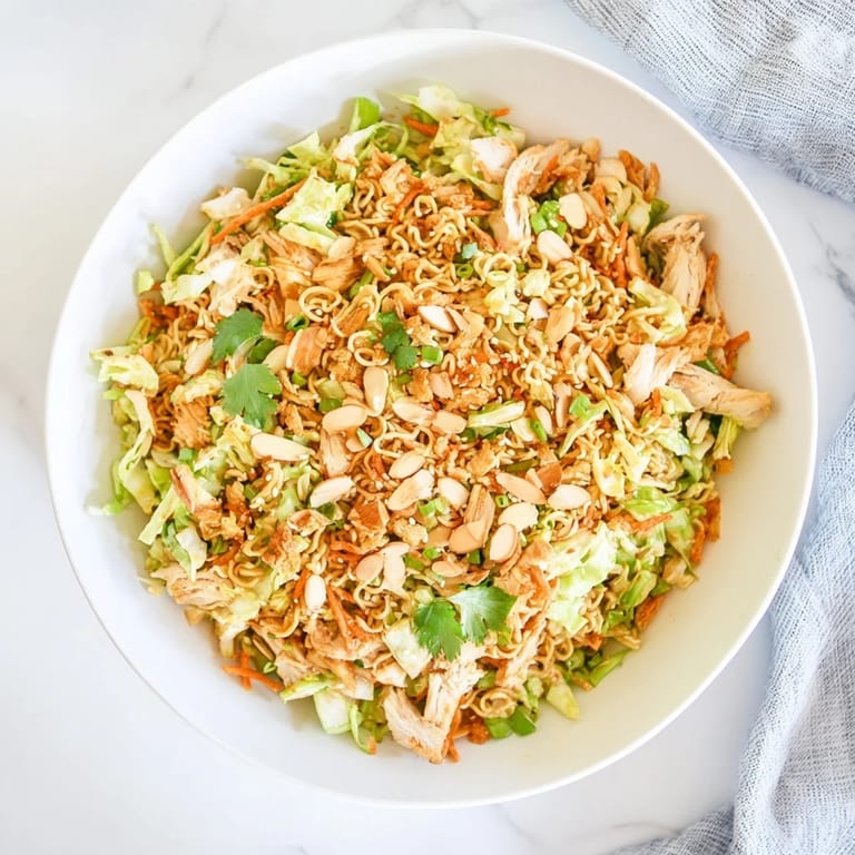 A vibrant serving of crunchy ramen chicken salad garnished with cilantro and scallions, perfect for a potluck lunch.